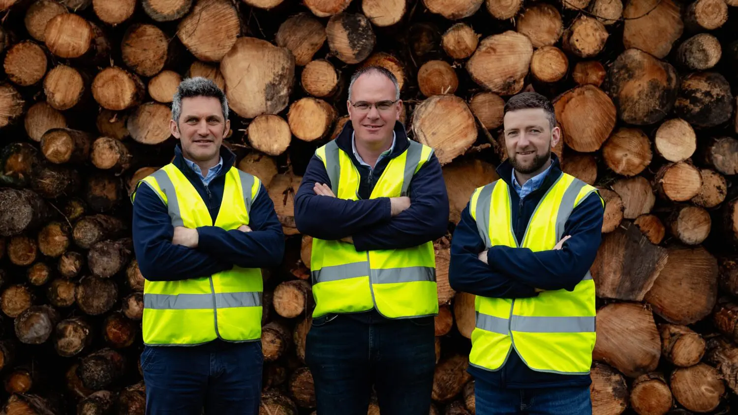 GP Wood team members in front of a log stack